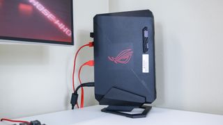 The Asus ROG NUC 970 stood up vertically on a desk next to a monitor