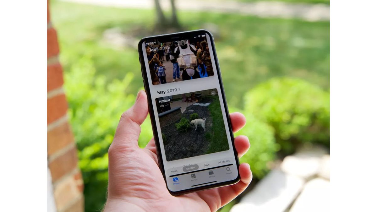 An iPhone XS Max displaying Photos in iOS 13 while being held in someone&#039;s hand.