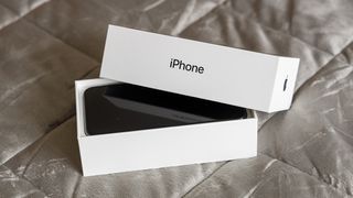iPhone Xs i sin kartong mot en grå bakgrund