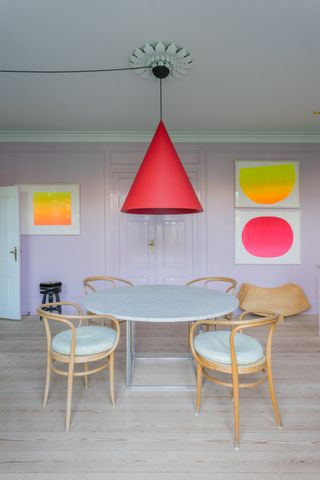 Lilac minimalist dining room with red pendant light and bright art on the walls
