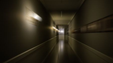 A white blur of motion is seen in a dark hallway.