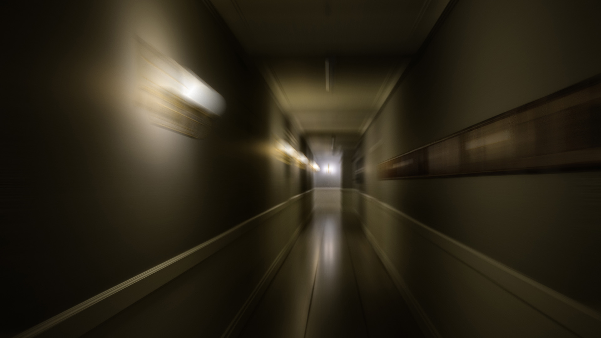 A white blur of motion is seen in a dark hallway.