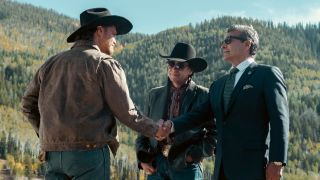 From left to right: Luke Grimes as Kayce, shaking Gil Birmingham's hand as he plays Rainwater. Mo Brings Plenty, who plays Mo, is standing to the left of Birmingham.