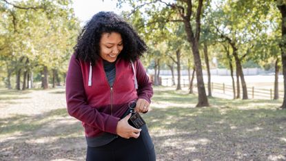 Woman checks insulin pump and blood sugar monitor while walking outdoors