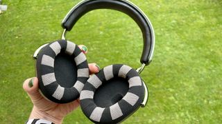 MW75 Neuro headphones held in a hand on green background