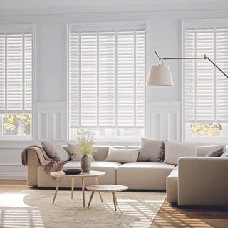 living area with window with white shutter and corner sofaa and wooden floor