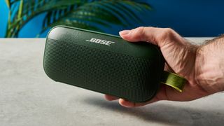 a green bluetooth speaker made by bose with a clean plastic casing and no visible woofers rests on a table