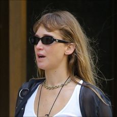 Jennifer Lawrence wearing khaki pants, flip-flops in fall, a white vest and sunglasses