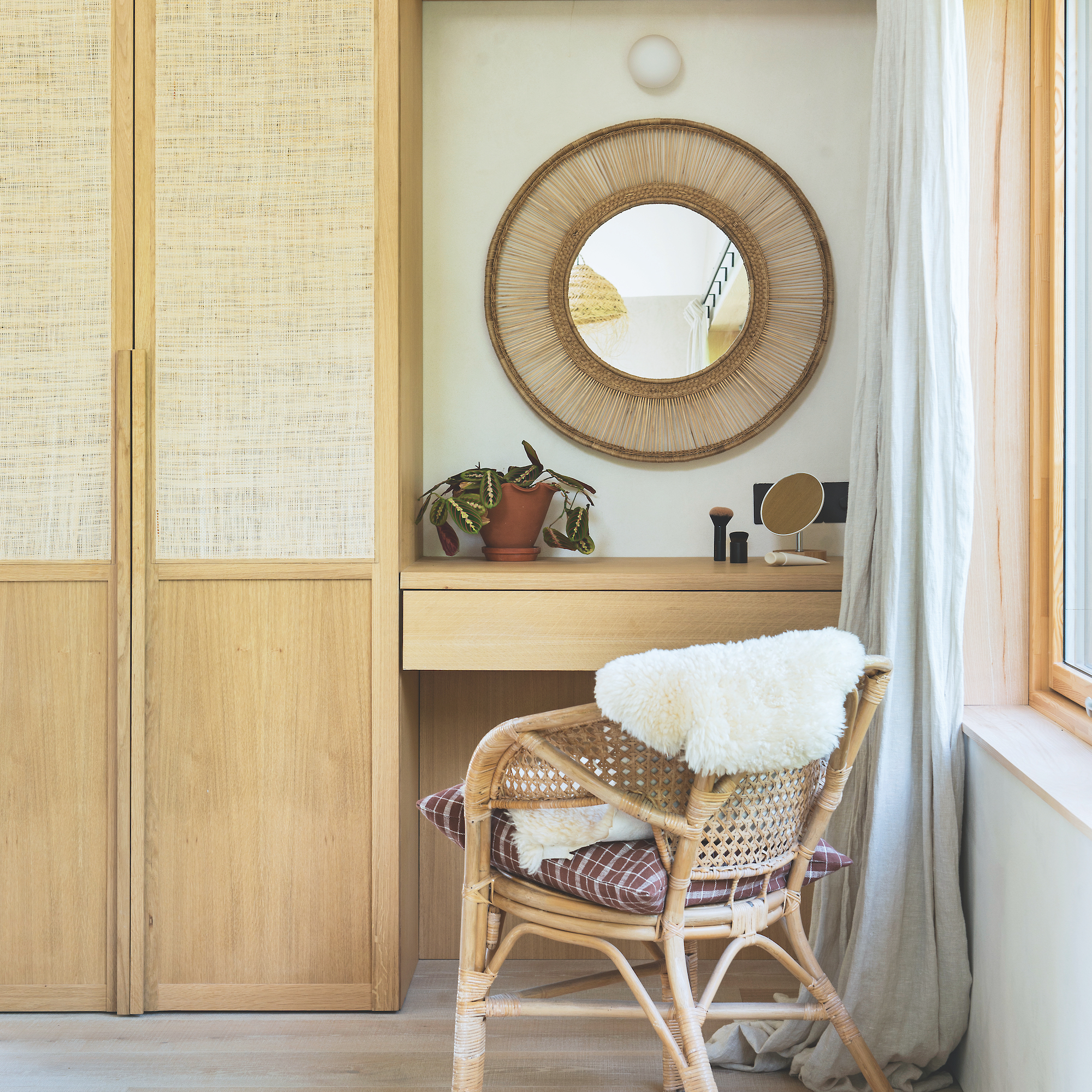 image of bedroom with built-in wooden cupboards and a small dressing table area with shelf drawer, circular mirror on wall and wooden chair
