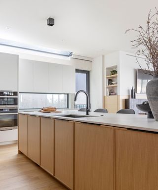A kitchen with wooden cabinetry and white blended countertops