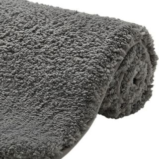 A fluff grey bathmat partially rolled up