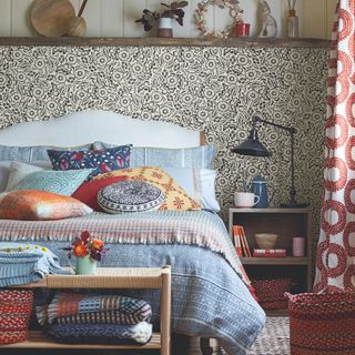 bedroom with lots of cushions and patterned wallpaper