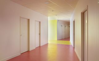 Interior corridor at the Lilas Animation Centre in Paris, white walls, white suspended tiled ceiling, spotlights, white doors, red floor