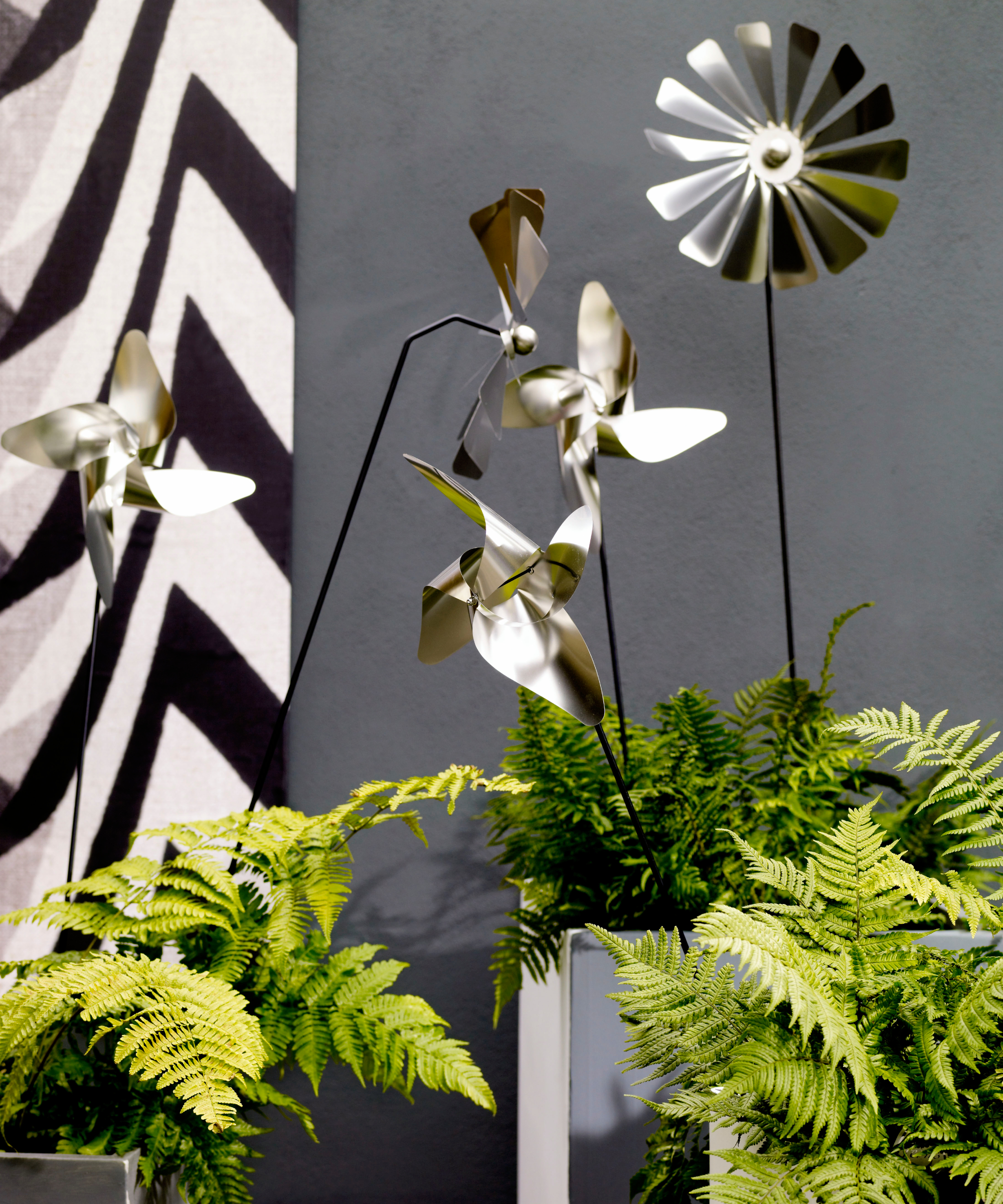 Metallic wind spinners pushed into planters in a modern garden