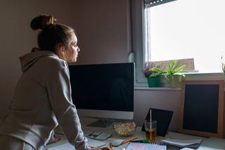 How to protect your eyes as a digital artist; a woman stands over a computer desk and looks out of a window