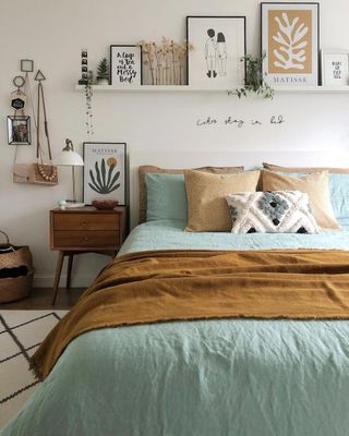 A bedroom with a blue and brown bed, a nightstand, and a wall shelf with decorations