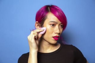 A person applies product to their face.