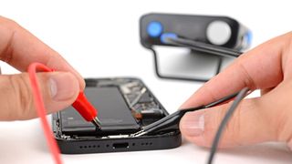 A person removes the battery from Apple's iPhone 16e using a small application of electricity.