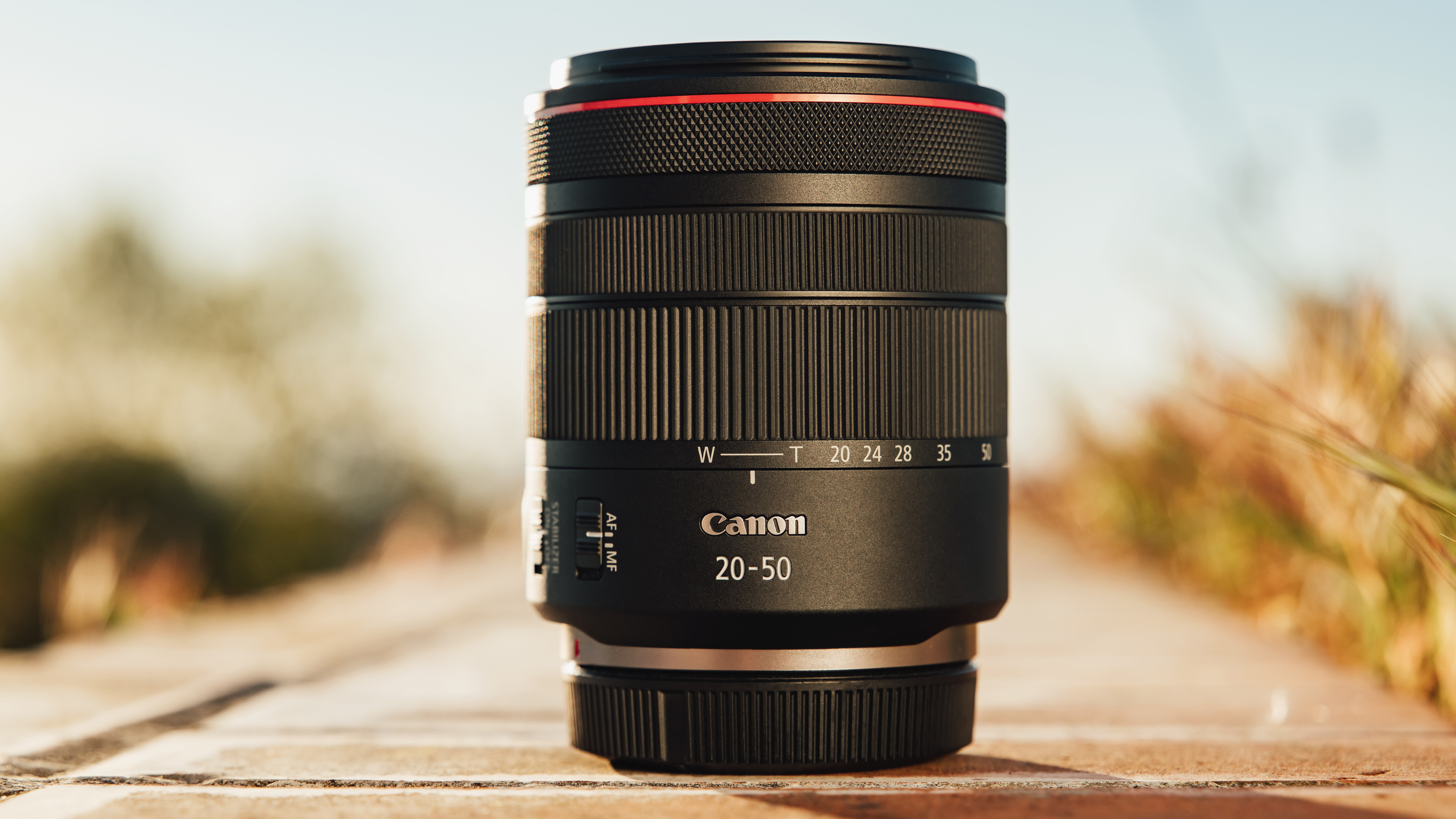 Canon RF 20-50mm f/4L IS USM PZ lens on a wooden surface outdoors