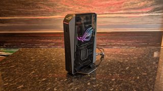 The Asus ROG NUC photographed on a dark marbled worksurface with a painted sunset in the background.