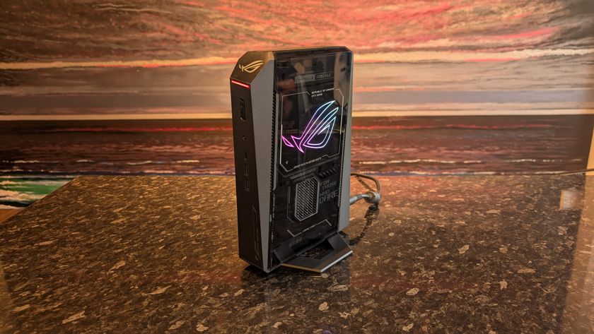 The Asus ROG NUC photographed on a dark marbled worksurface with a painted sunset in the background.
