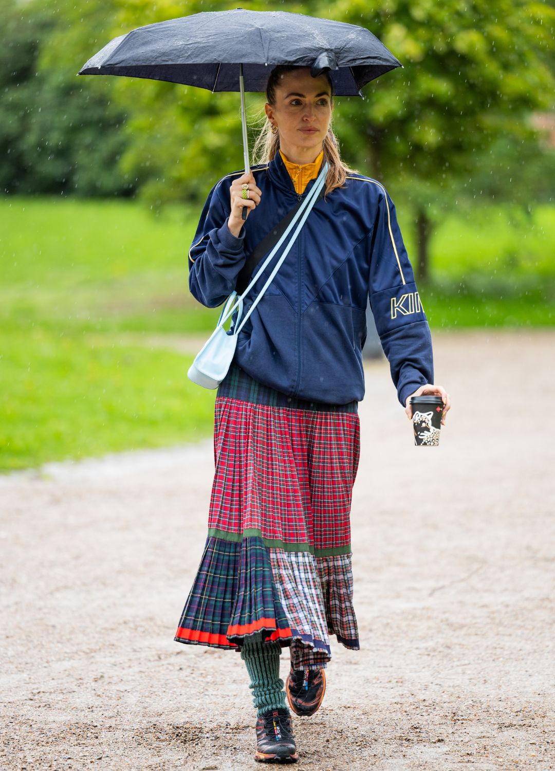 A guest wears blue track suit jacket, checkered multi colored skirt outside OpéraSport during the Copenhagen Fashion Week Spring/Summer 2024 on August 09, 2023 in Copenhagen, Denmark.