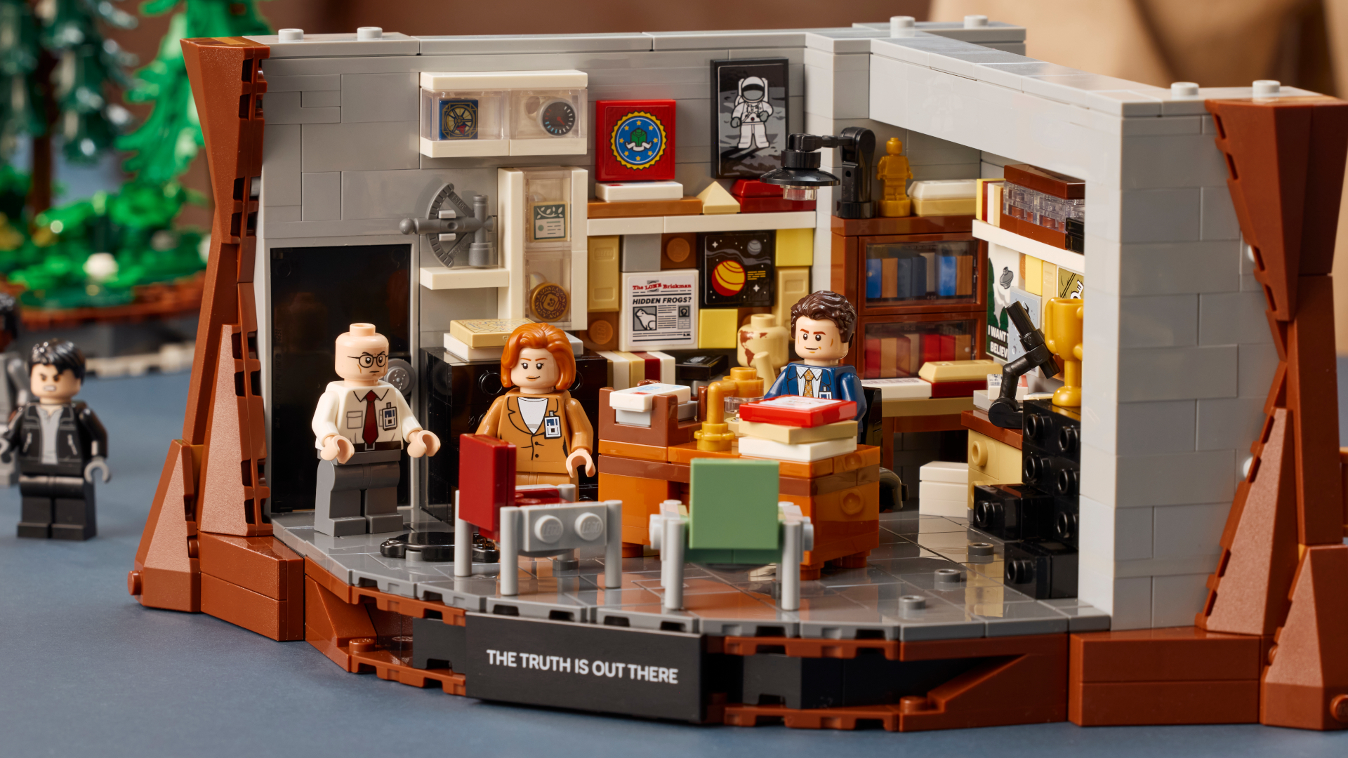 Lego Mulder's office laid out on a table with minifigures behind and in front of the desk
