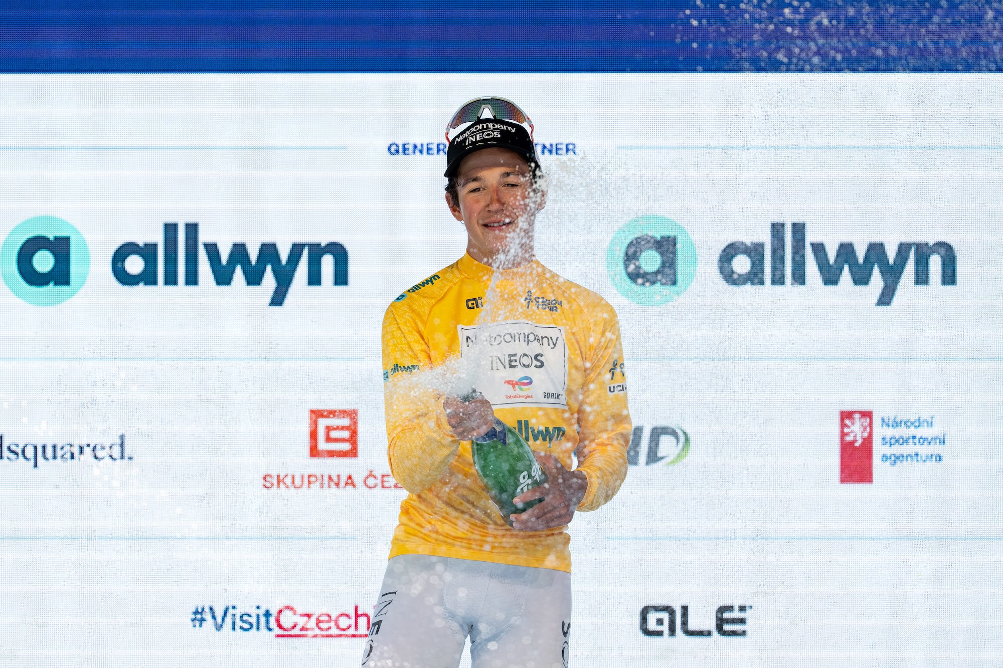 Andrew August of the United States and Team Netcompany - INEOS celebrates on the podium as the stage winner and leader of the general, points, and youth classifications (yellow, green, and white jerseys) after the second stage of the Czech Tour 2026, a 155km stage from Mlada Boleslav (Skoda Museum) to Jested (Jestedka Mountain Hut), on August 14, 2026 in Liberec, Czech Republic. (Photo by Filip Bezdek/NurPhoto via Getty Images)