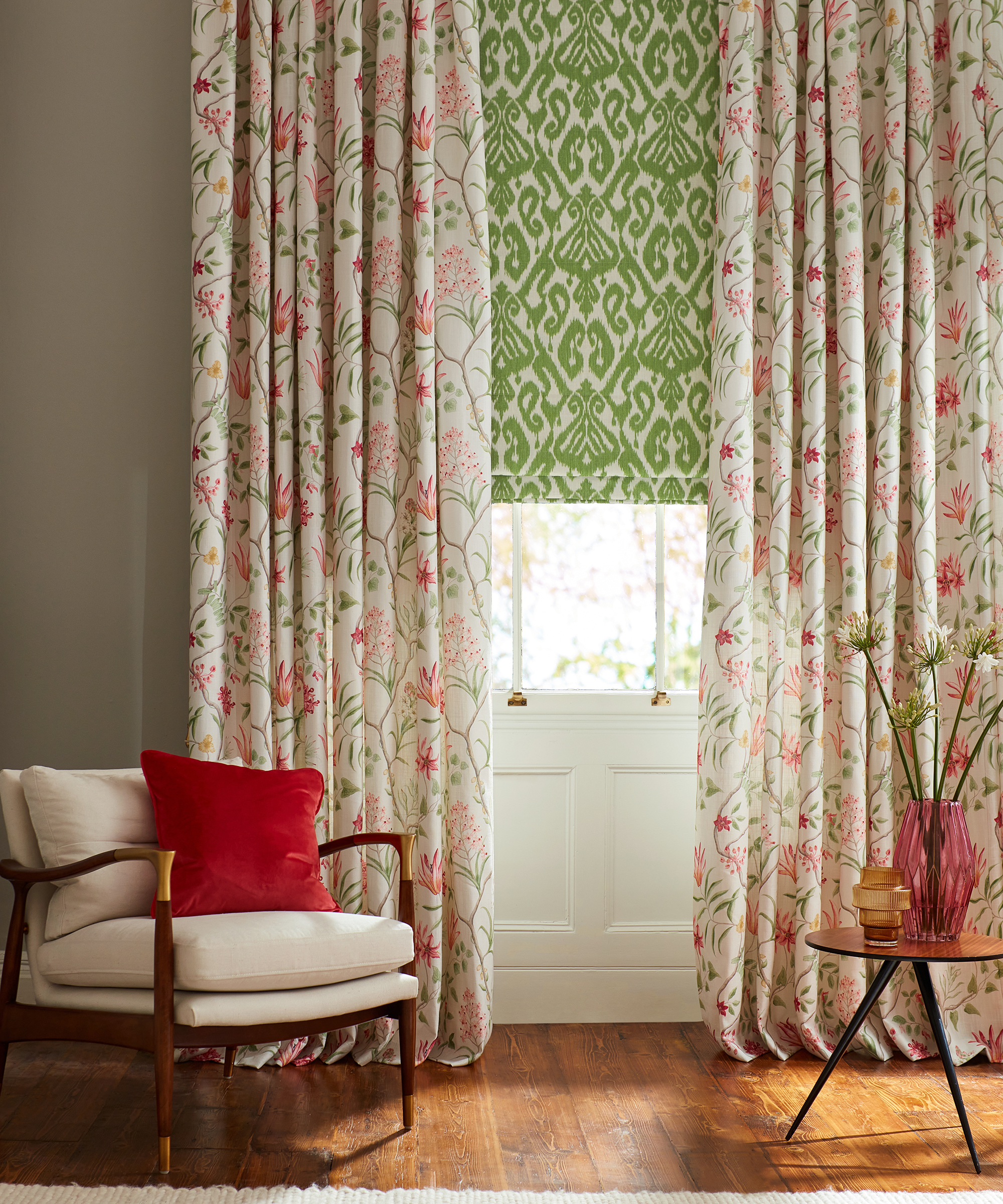 sash window with green patterned blind and full length floral curtains