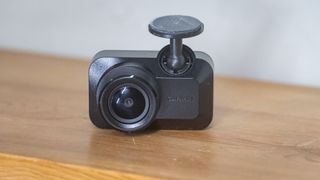 Garmin Mini 3 dashcam on a wooden table in front of a white wall