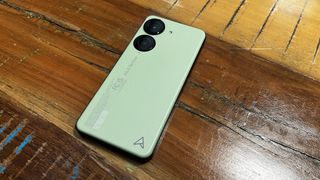 The Asus Zenfone 10 in green, on a wooden background