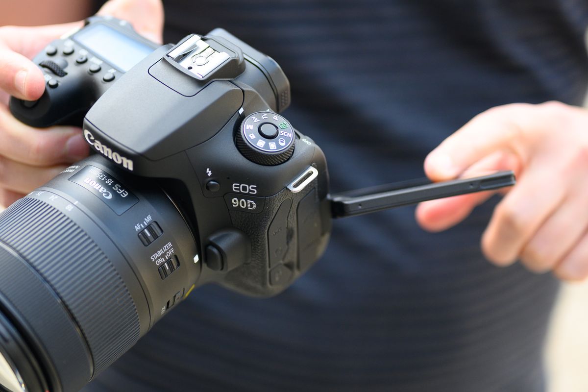 A hand holding the Canon EOS 90D camera