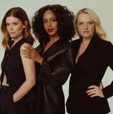 Kerry Washington, Elisabeth Moss, and Kate Mara pose in chic black outfits against a minimalist studio background.