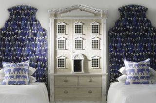 how to design a kid's room A dolls house with twin beds each side and upholstered bedheads in whimsical blue fabrics