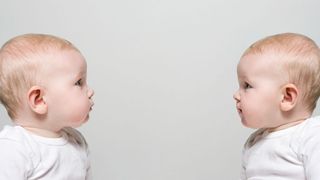 the faces of two twin babies sitting across from each other against a blank background