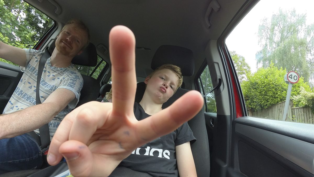 Boy doing peace sign in the passenger seat of a car, taken with the Insta360 Go 3S