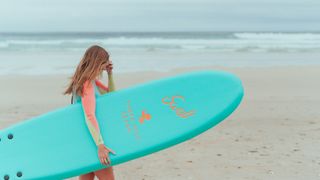 girl surfing at Three Mile Beach, Cornwall, UK