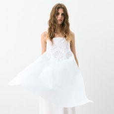 Woman wears shell-embroidered white dress