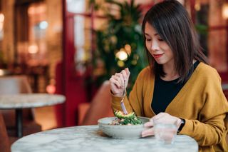 Vegan diet: Young Woman Eating Green Salad At Restaurant