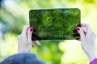 Hands of a woman using augmented reality on a high tech transparent digital tablet