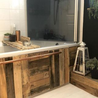 Bath surround built from upcycled rustic wooden boards with a hanging rail made from copper piping
