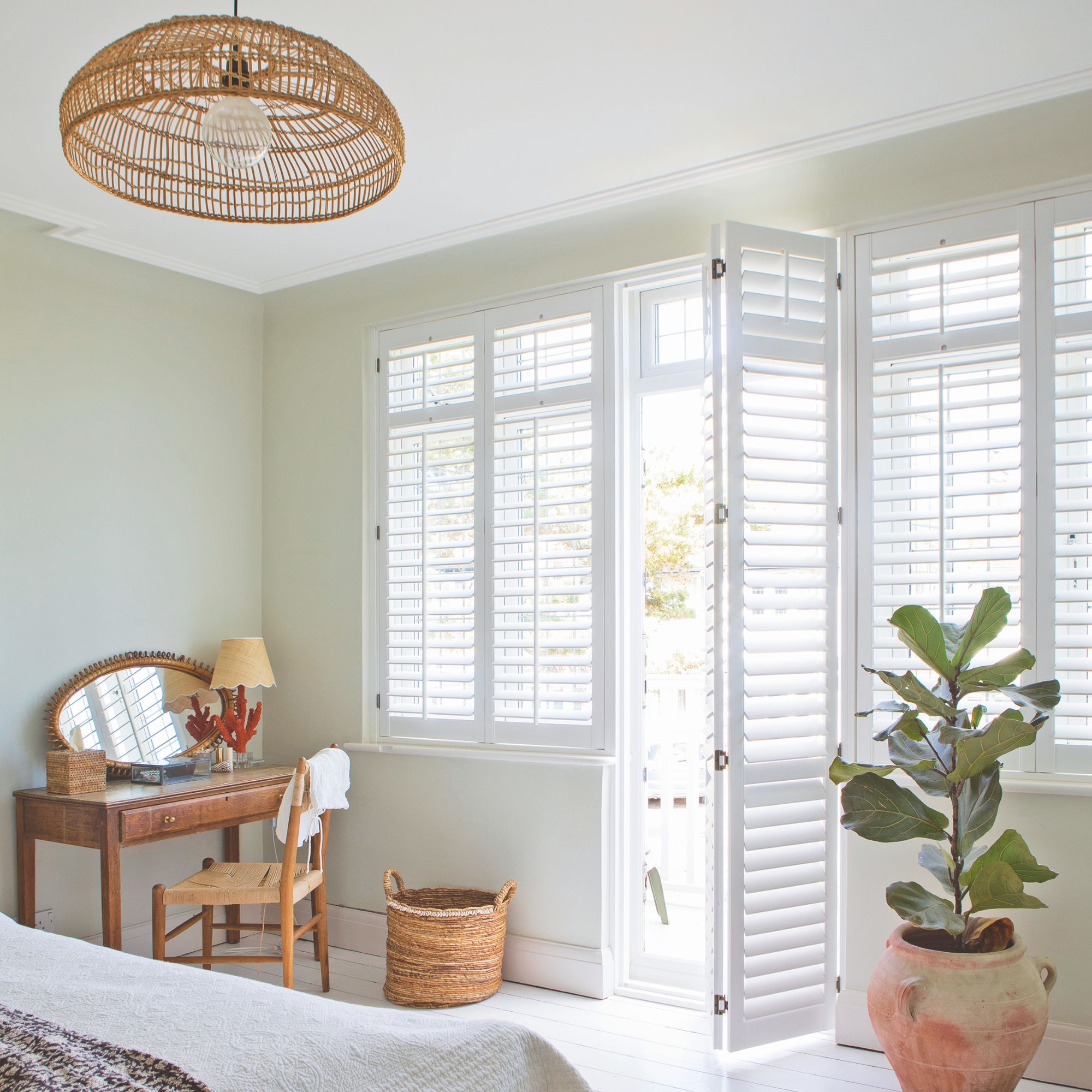 A neutral bedroom with wood accents, shutter blinds and an open door