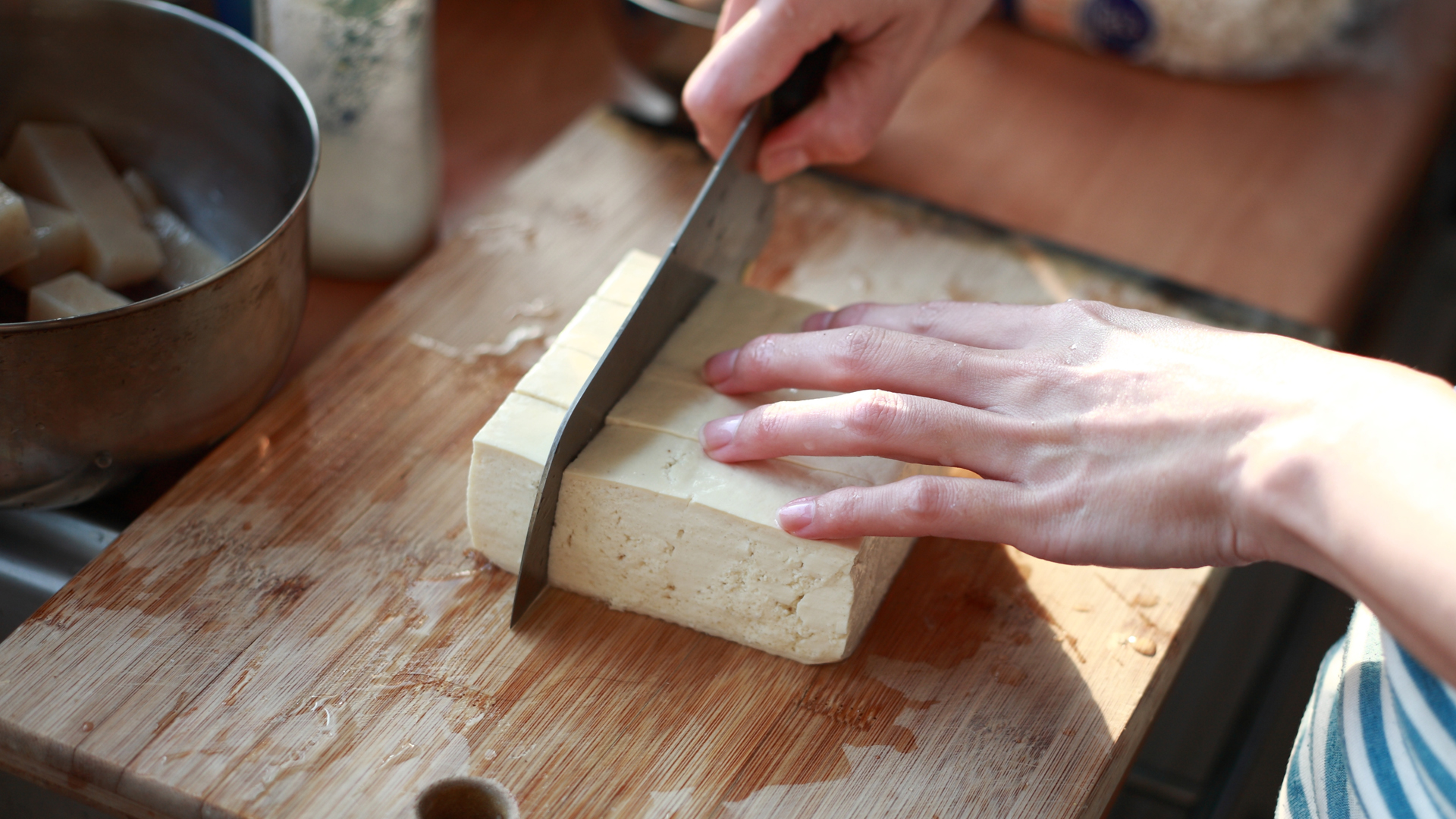 person cutting a block of tofu