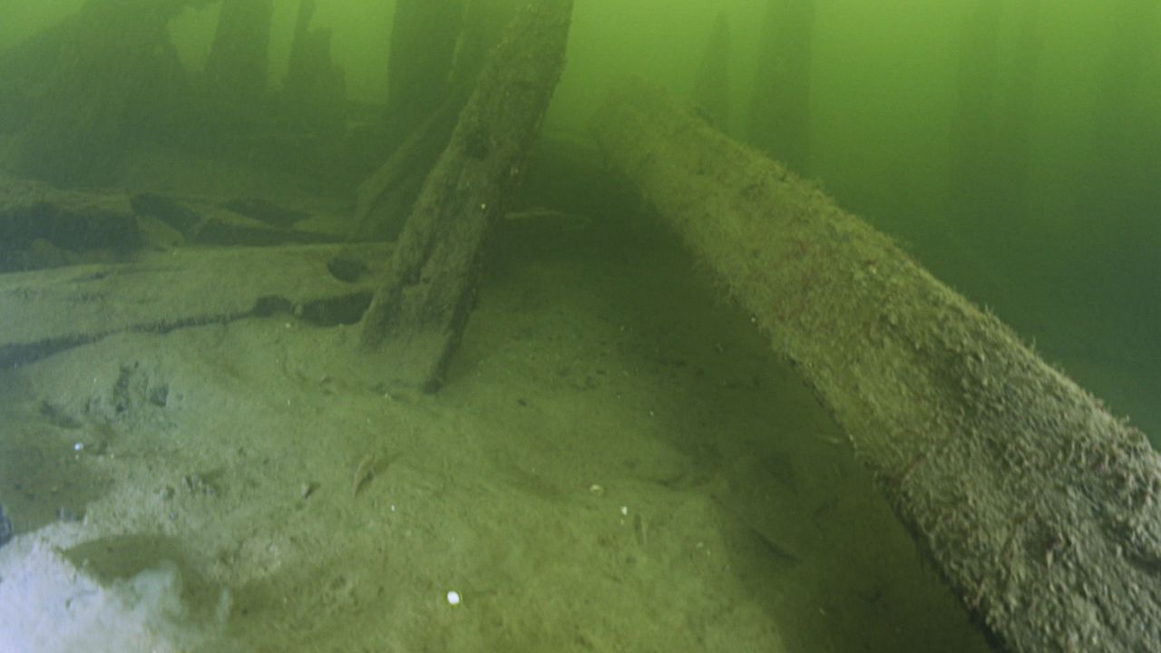 An underwater view of a shipwreck in murky green water