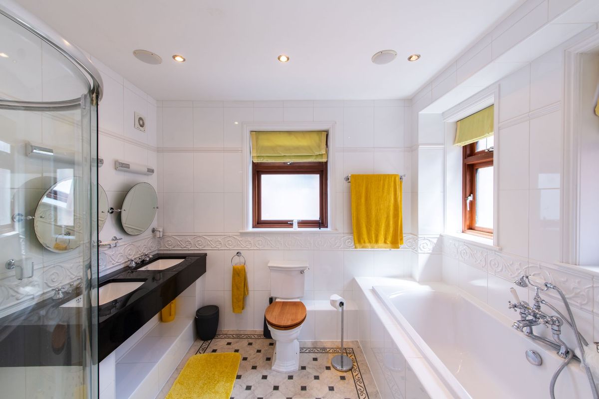 The bathroom has black sink tops and white bath and a walk in shower