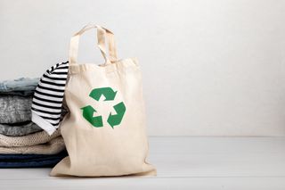 Second-hand clothing with a tote bag with the recycling symbol on.