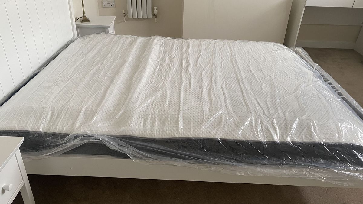Otty Original Hybrid mattress in plastic on a bed frame