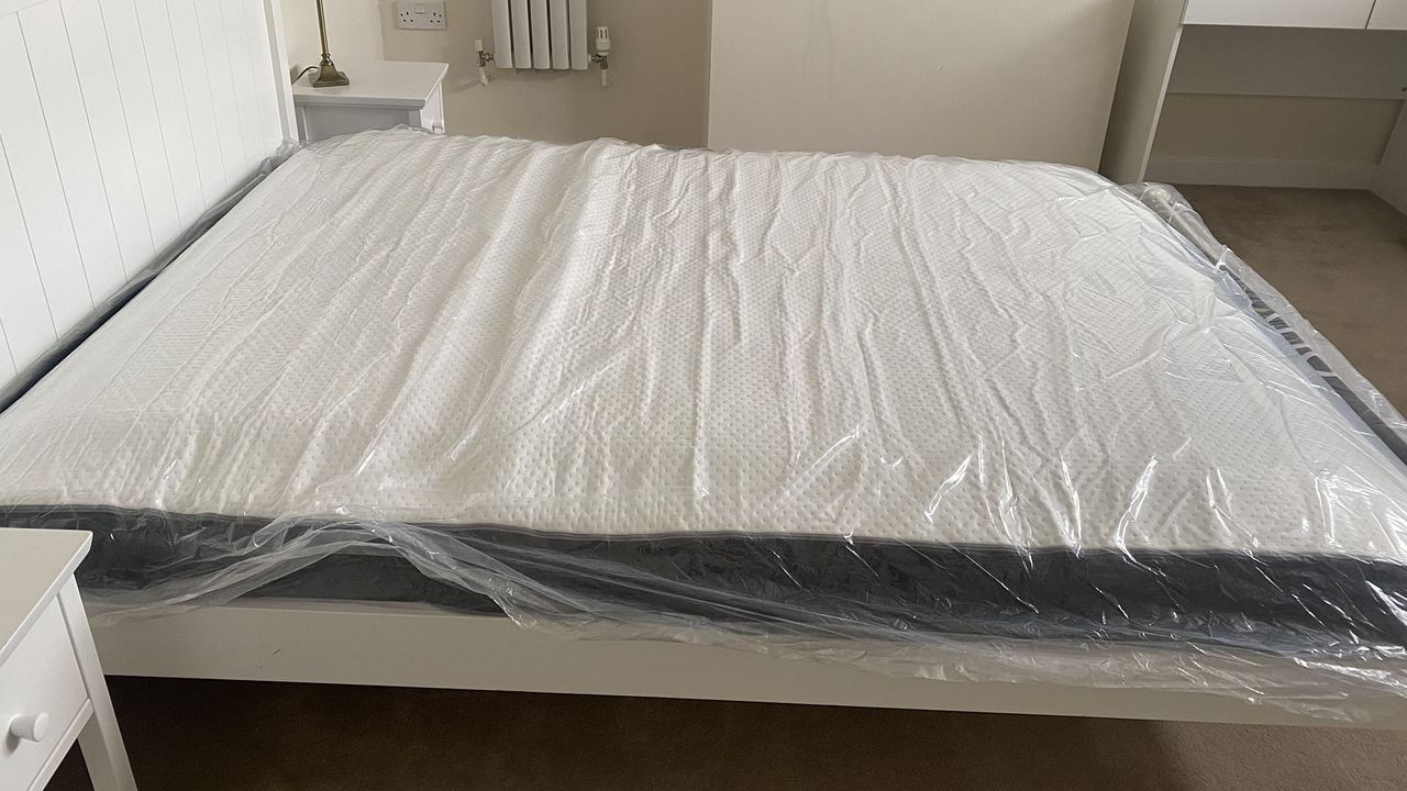 Otty Original Hybrid mattress in plastic on a bed frame