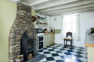 kitchen with stone fireplace, cabinets and checkerboard tile floors