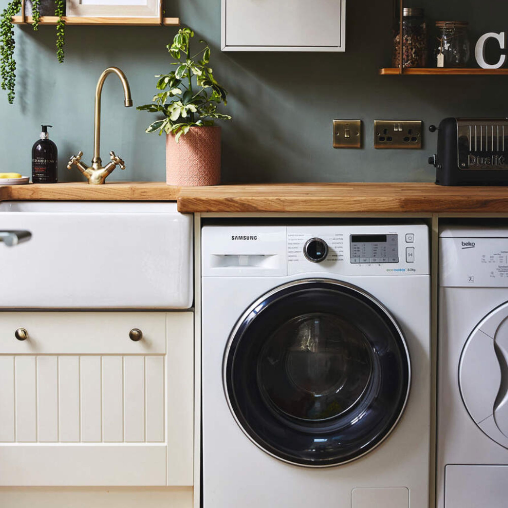 A green kitchen with a built in washing machine